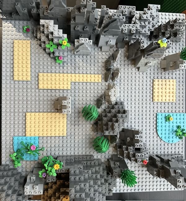 LEGO cliff terrain build with vegetation, uneven slopes, and natural choke points